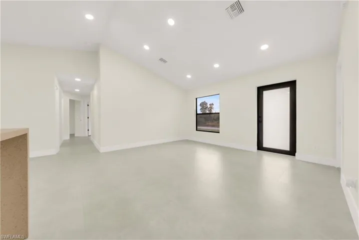 Empty room featuring vaulted ceiling and recessed lighting
