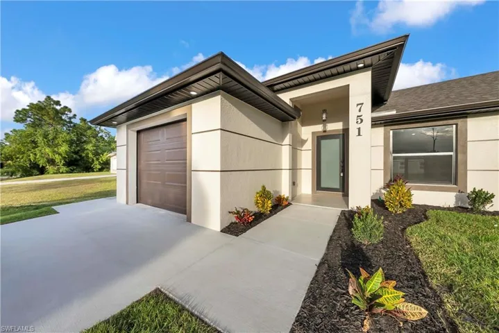 View of front of property featuring stucco siding, an attached garage, driveway, and a front lawn