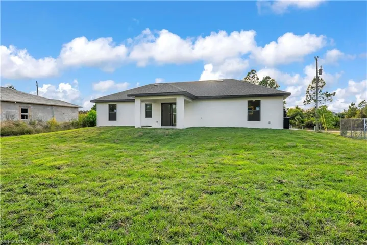Rear view of property with a yard, stucco siding, and a patio