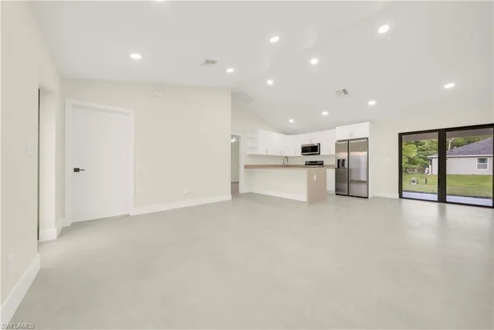 Unfurnished living room with recessed lighting, finished concrete floors, and lofted ceiling