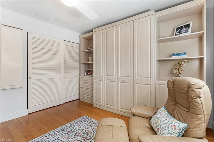 Guest bedroom features wood floors, plantation shutters, and Murphy bed
