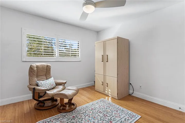 Guest bedroom features wood floors, plantation shutters, and Murphy bed