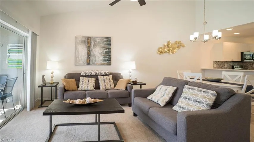 Living room with carpet flooring, a chandelier, recessed lighting, vaulted ceiling, and a ceiling fan