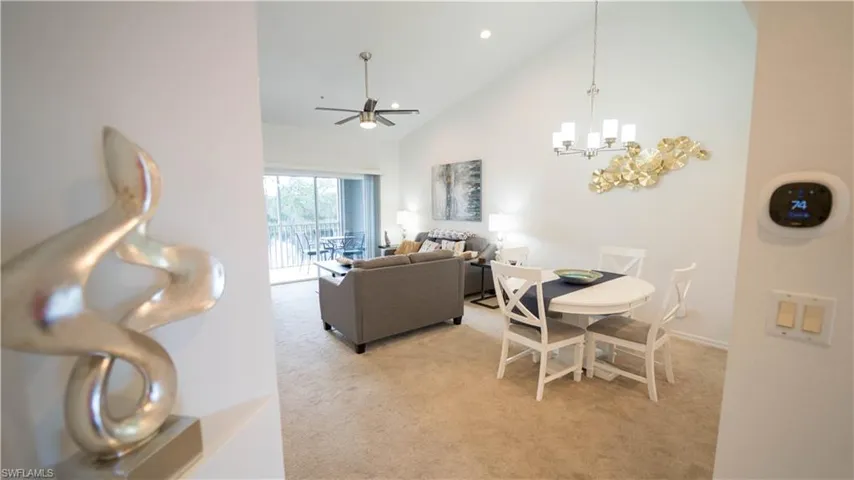 Dining area with high vaulted ceiling, light carpet, a chandelier, ceiling fan, and recessed lighting