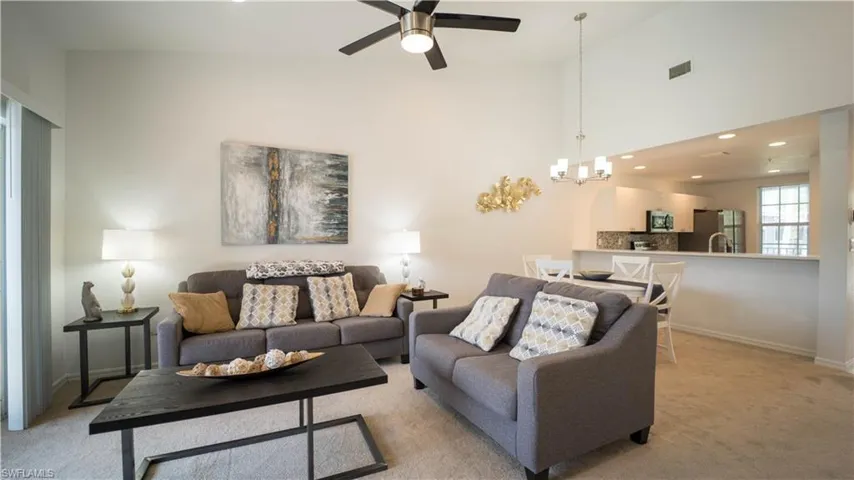 Living area featuring recessed lighting, carpet, ceiling fan, a high ceiling, and a chandelier