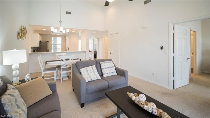 Carpeted living area featuring a high ceiling, a chandelier, and a ceiling fan