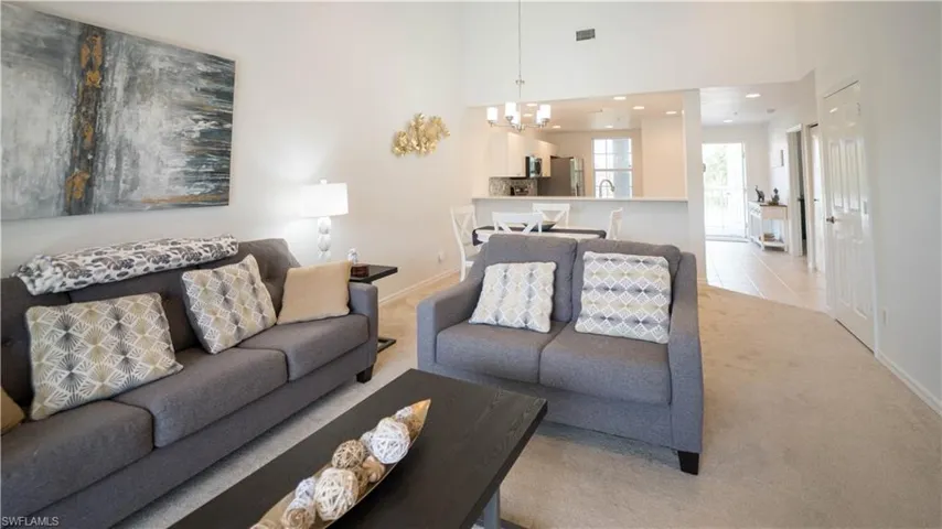 Carpeted living room with a high ceiling, a chandelier, recessed lighting, and tile patterned floors