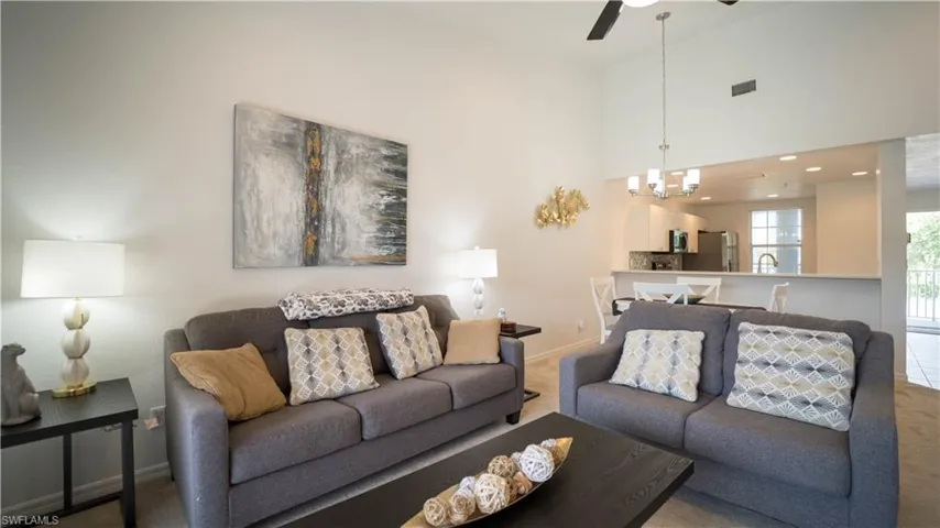 Living area with carpet, a high ceiling, a ceiling fan, a chandelier, and recessed lighting
