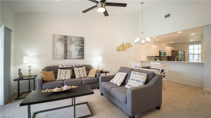 Living area with recessed lighting, carpet floors, ceiling fan, a high ceiling, and a chandelier