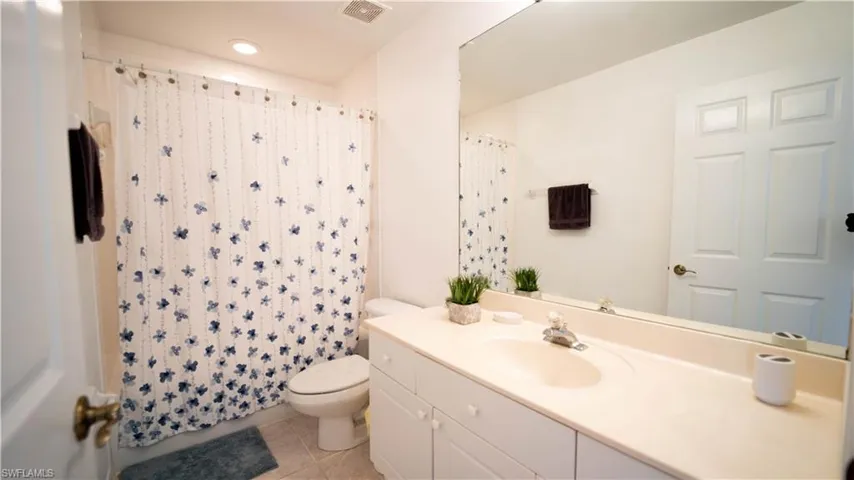 Bathroom featuring vanity, light tile patterned flooring, and curtained shower