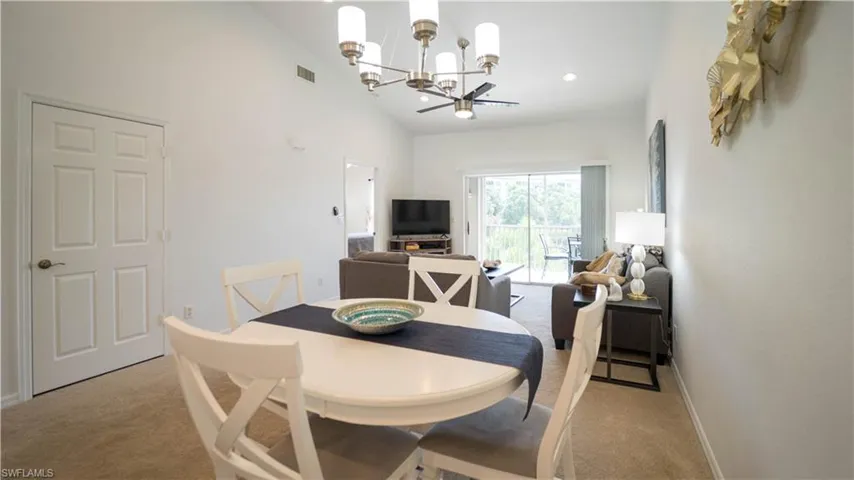 Dining room featuring a chandelier, vaulted ceiling, light carpet, and recessed lighting