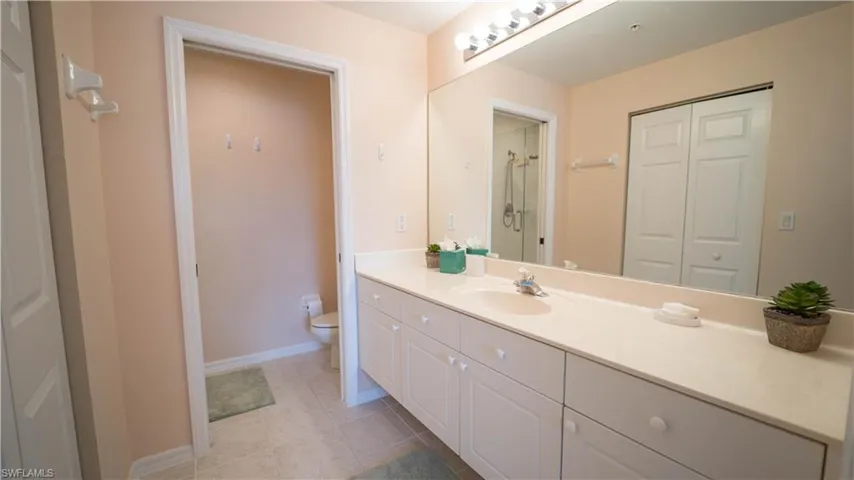 Full bathroom with vanity, light tile patterned floors, a closet, and a shower