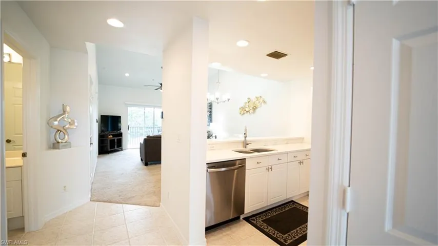 Kitchen featuring light colored carpet, dishwasher, a chandelier, white cabinets, and light tile patterned floors
