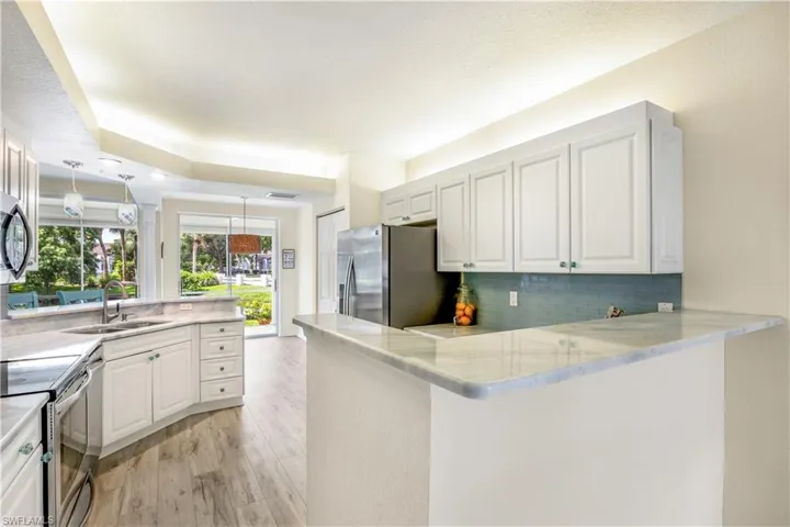 Kitchen with white cabinetry, kitchen peninsula, new LTV flooring, and stainless steel appliances