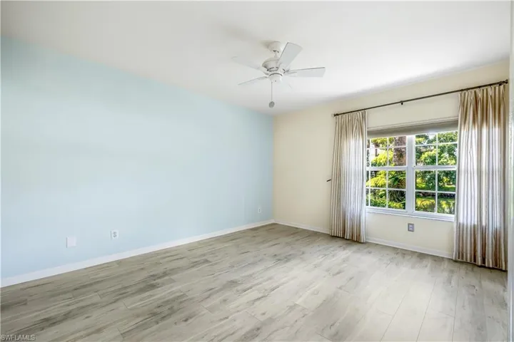 Master Bedroom featuring new LTV flooring, accent painted wall, ceiling fan, and exterior door to screened lanai