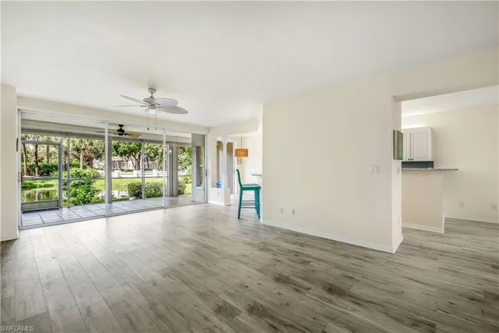 Living room area with new LTV flooring, ceiling fan and a slider to outside screened lanai.