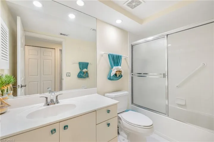 Full guest bathroom with tile patterned flooring, toilet, vanity, and enclosed tub / shower combo