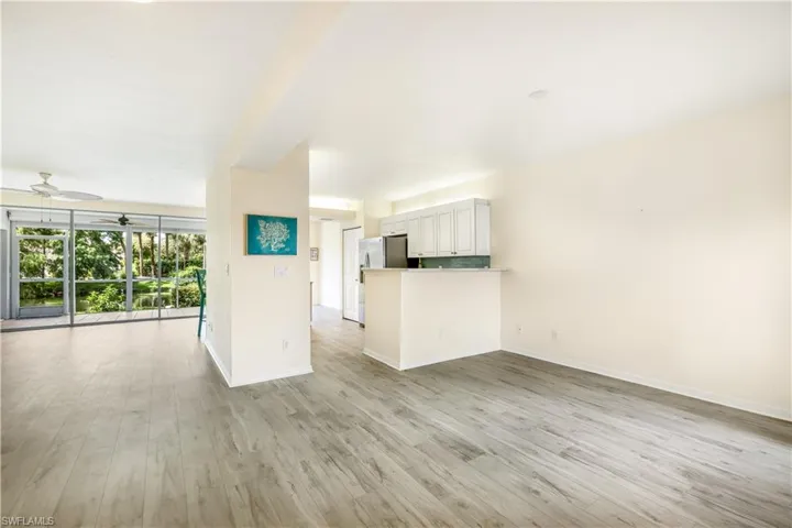 Living room with bonus area off the kitchen featuring new LTV flooring and ceiling fan
