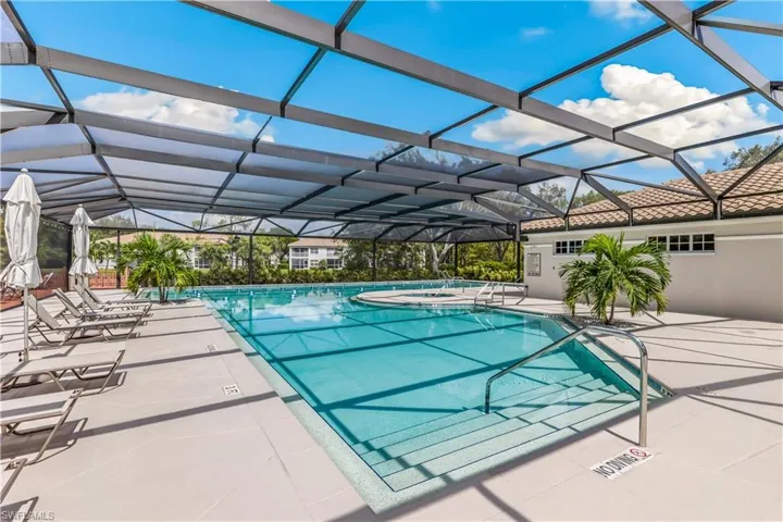 View of pool featuring an in ground hot tub, a patio area, and glass enclosure