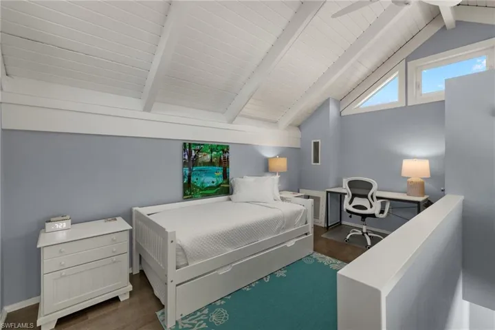 Loft with ceiling fan, dark hardwood / wood-style flooring, and lofted ceiling with beams