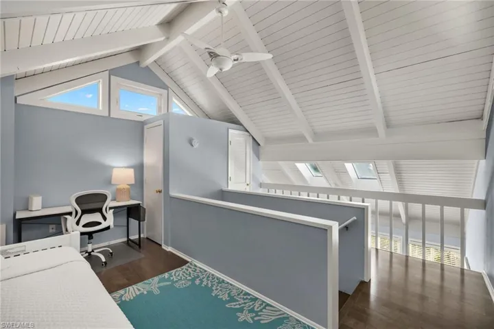 Loft area featuring a wealth of natural light, dark hardwood / wood-style floors, lofted ceiling with skylight, and ceiling fan