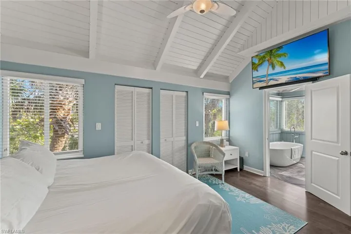 Bedroom featuring wooden ceiling, vaulted ceiling with beams, ceiling fan, dark hardwood / wood-style floors, and multiple closets