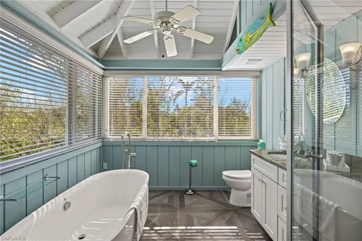 Bathroom featuring parquet flooring, a washtub, vanity, lofted ceiling with beams, and toilet