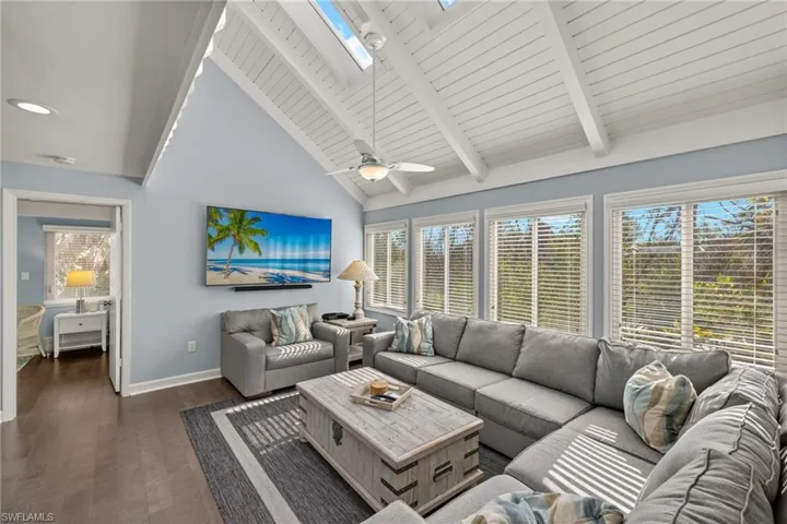 Living room featuring wood ceiling, ceiling fan, lofted ceiling with skylight, and dark hardwood / wood-style floors