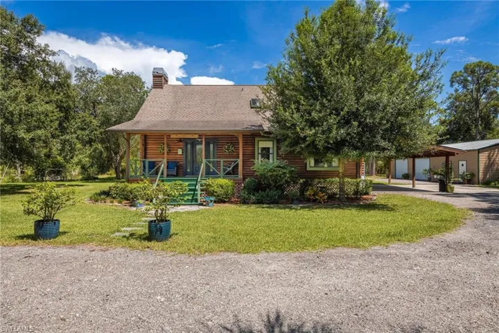 Cypress log home featuring 5 acres, large front potch, carport, and detached garage.