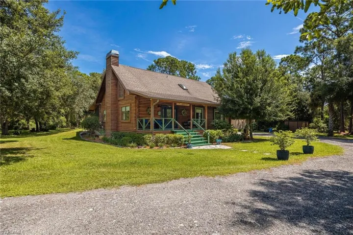 Log house with a beautiful front lawn and spacious front porch.