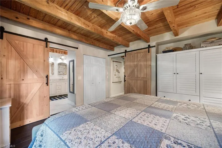 Downstairs Master Bedroom bedroom featuring ensuite bathroom, beamed ceiling, a barn door, and wooden ceiling