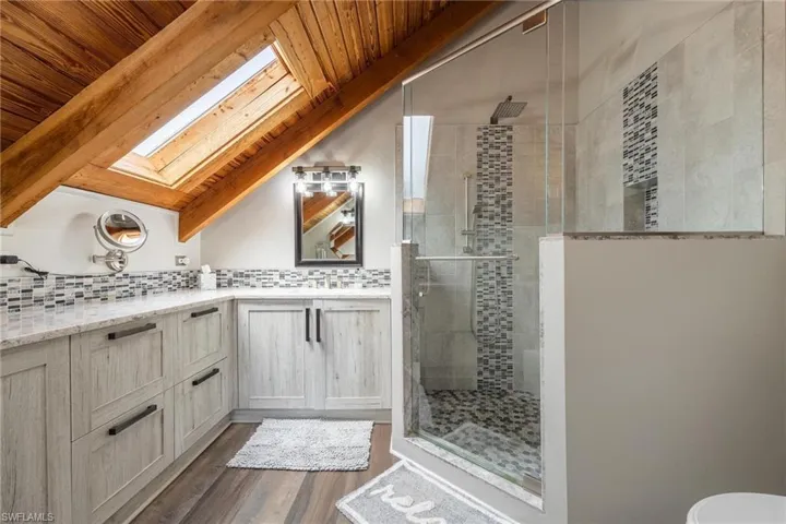 Upstairs Master Bathroom with vaulted ceiling with skylight, vanity, wood-type flooring, wood ceiling, and a shower with door