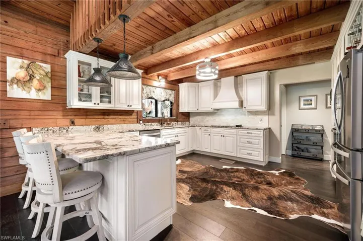 Kitchen featuring hanging light fixtures, custom range hood, and wood ceiling