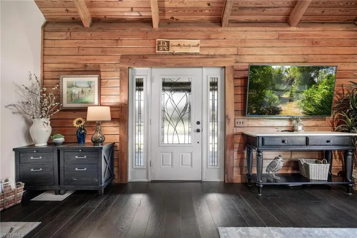 Entrance foyer with wooden ceiling, dark hardwood / wood-style floors, wooden walls, and beam ceiling