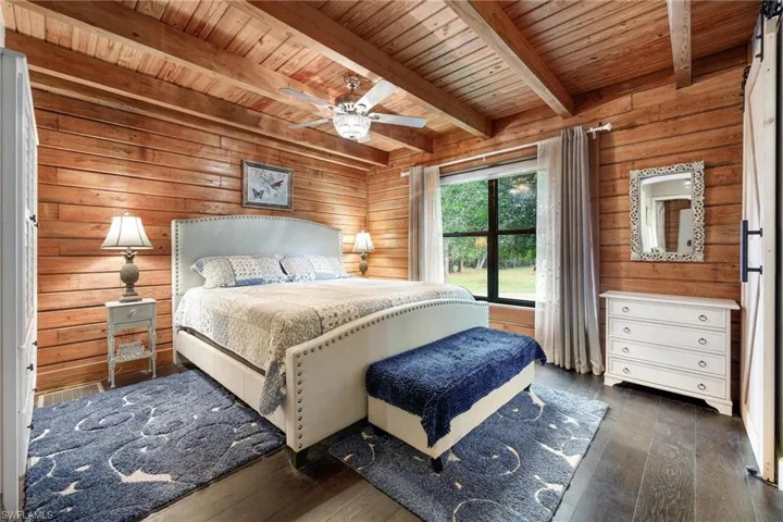 Downstairs Master Bedroom featuring ceiling fan, wooden ceiling, beamed ceiling, and dark hardwood / wood-style floors