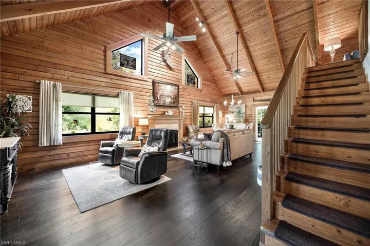 Living room with high vaulted ceiling, plenty of natural light, wooden ceiling, and dark wood-type flooring
