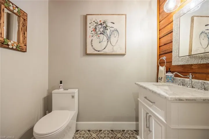 Downstairs half bath with toilet, vanity, and tile patterned floors