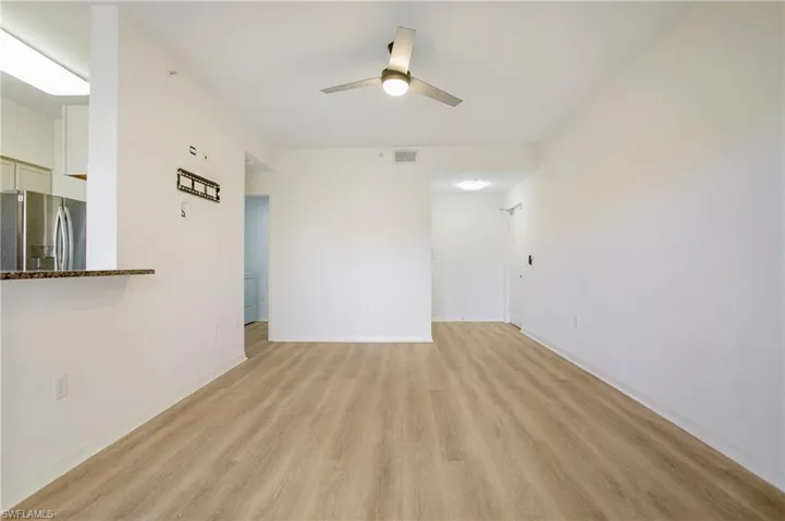 Empty room featuring light wood-style floors, a ceiling fan, and baseboards