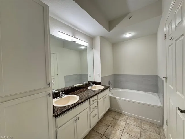 Bathroom with double vanity, a garden tub, and tile patterned flooring