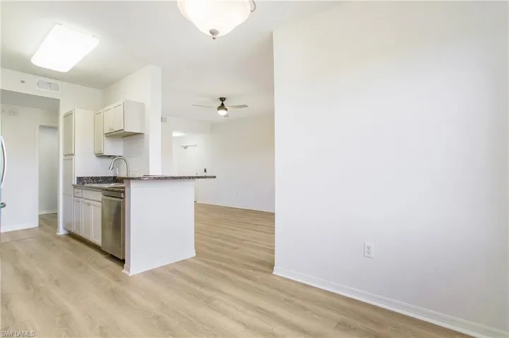 Kitchen featuring stainless steel dishwasher, light wood-style floors, ceiling fan, baseboards, and a sink
