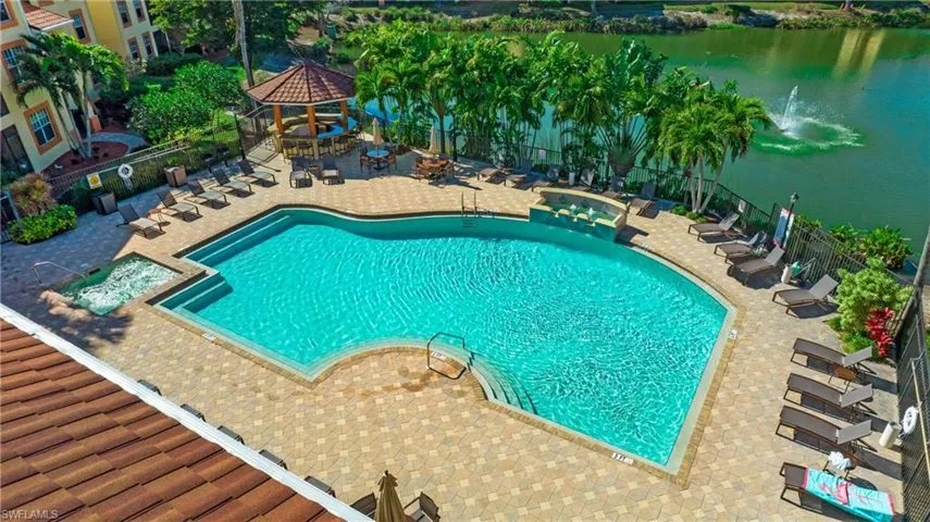 View of pool with a gazebo, a pool with connected hot tub, a patio area, and a water view