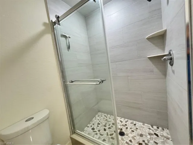 Bathroom with a shower stall and toilet