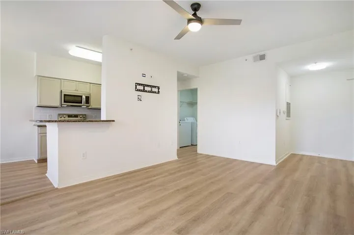 Unfurnished living room featuring light wood-style floors, a ceiling fan, and baseboards