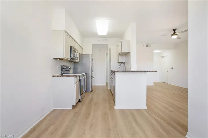 Kitchen featuring appliances with stainless steel finishes, dark countertops, light wood-type flooring, and baseboards