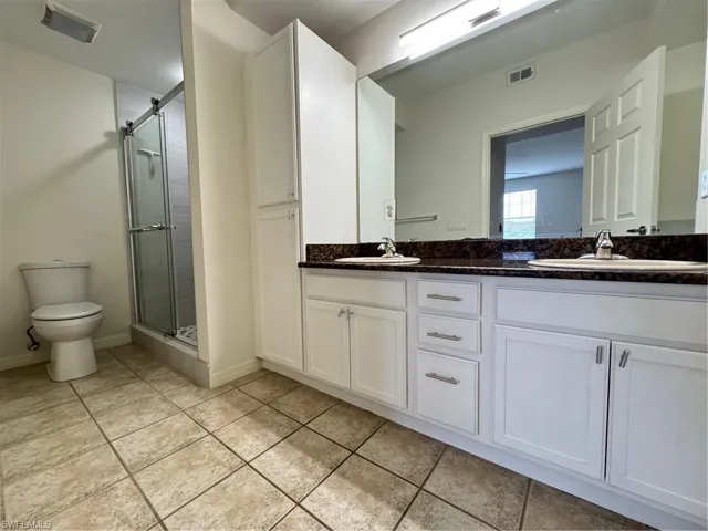 Bathroom featuring double vanity, a shower stall, and tile patterned floors