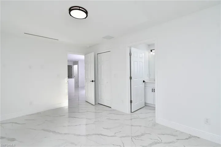 Unfurnished bedroom with light marble finish flooring, a closet, and ensuite bath
