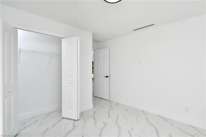 Unfurnished bedroom with a closet and light marble finish floors