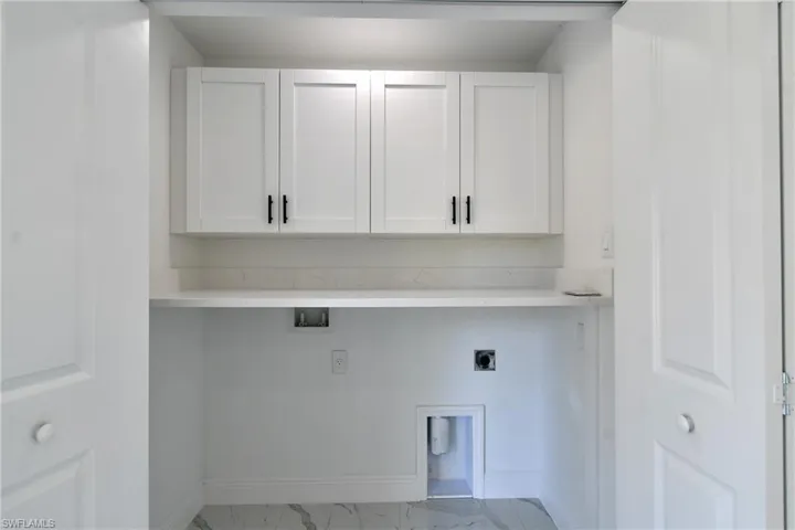 Washroom featuring light marble finish floors, cabinet space, hookup for an electric dryer, and washer hookup