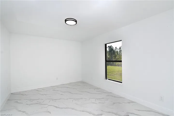 Unfurnished room featuring light marble finish floors and baseboards