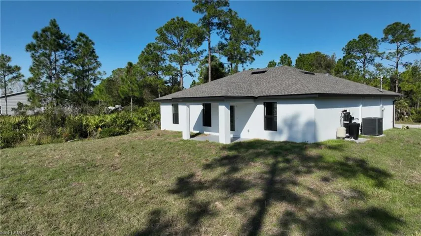 Rear view of property featuring stucco siding, a yard, a patio, and roof with shingles